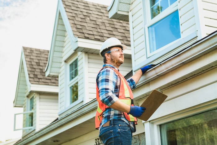 man using maintenance checklist to inspect gutters at home