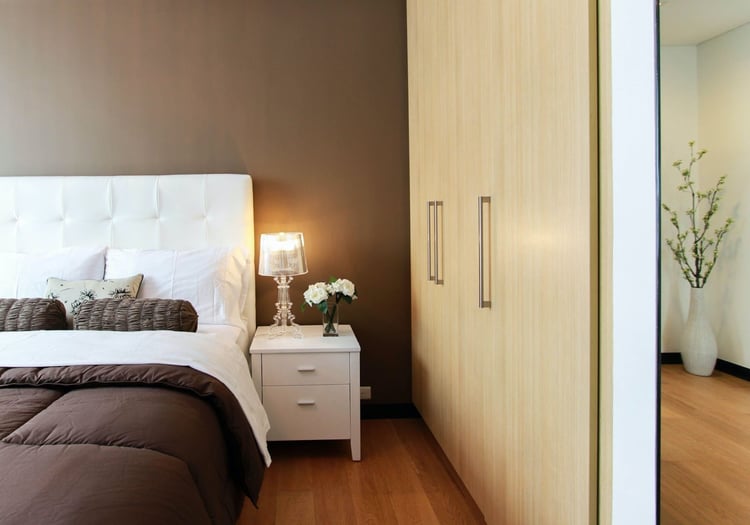 Master bedroom with bedside table, bedside lamp, and ample closet space