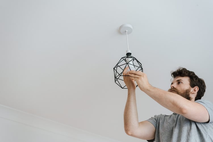 Man screwing in light bulb on ceiling light fixture